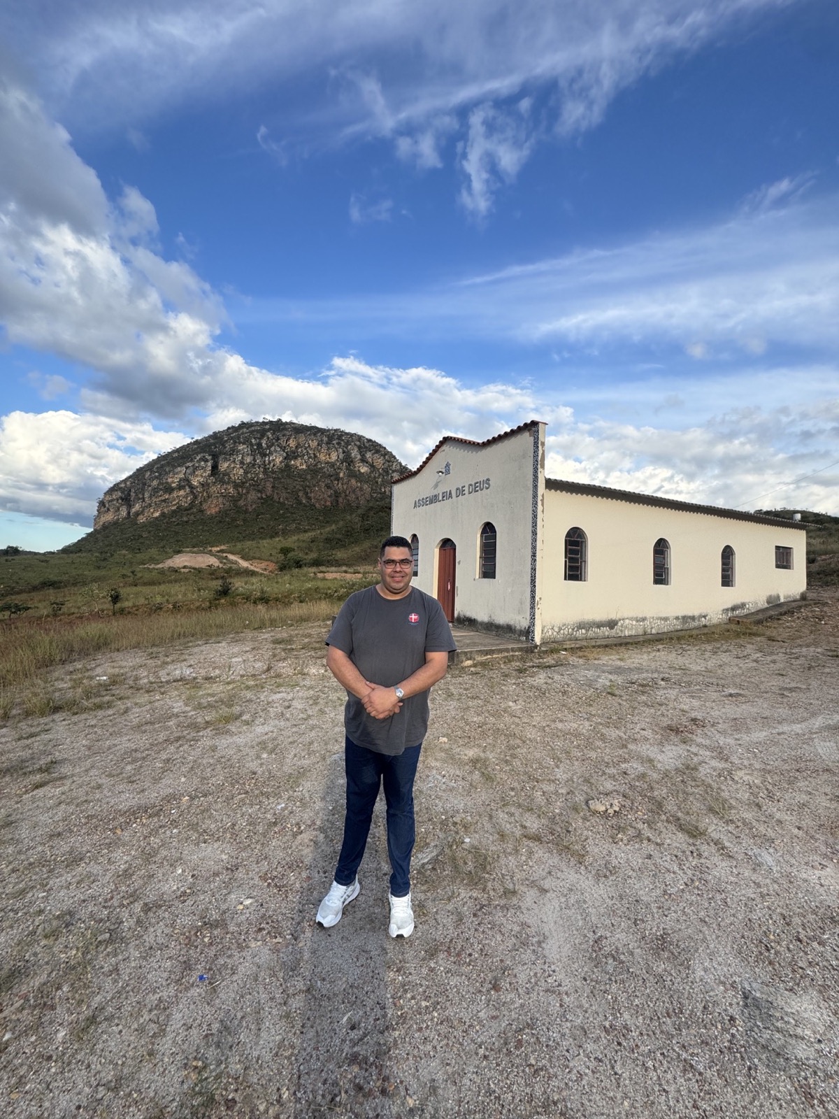 Missionário diante de uma igreja aos pés da serra no Brasil