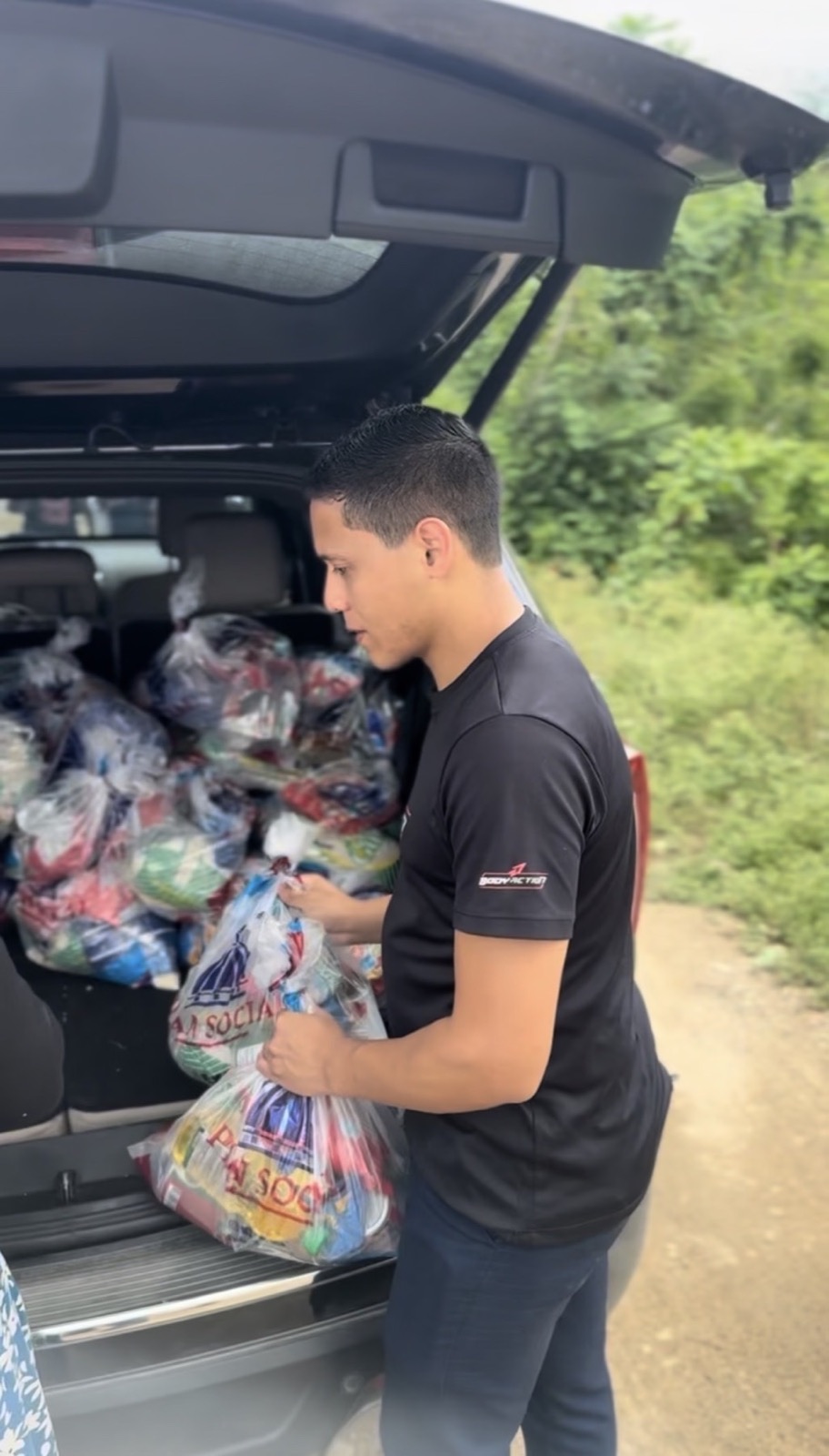 Missionário retirando bolsas de alimentos de um veículo na República Dominicana