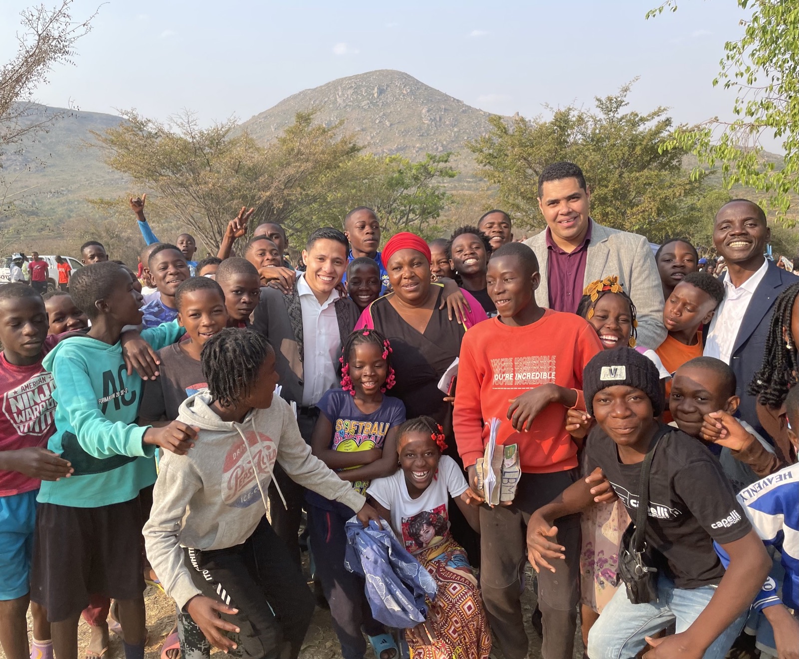 Missionários cercados por crianças e jovens diante das montanhas de Angola